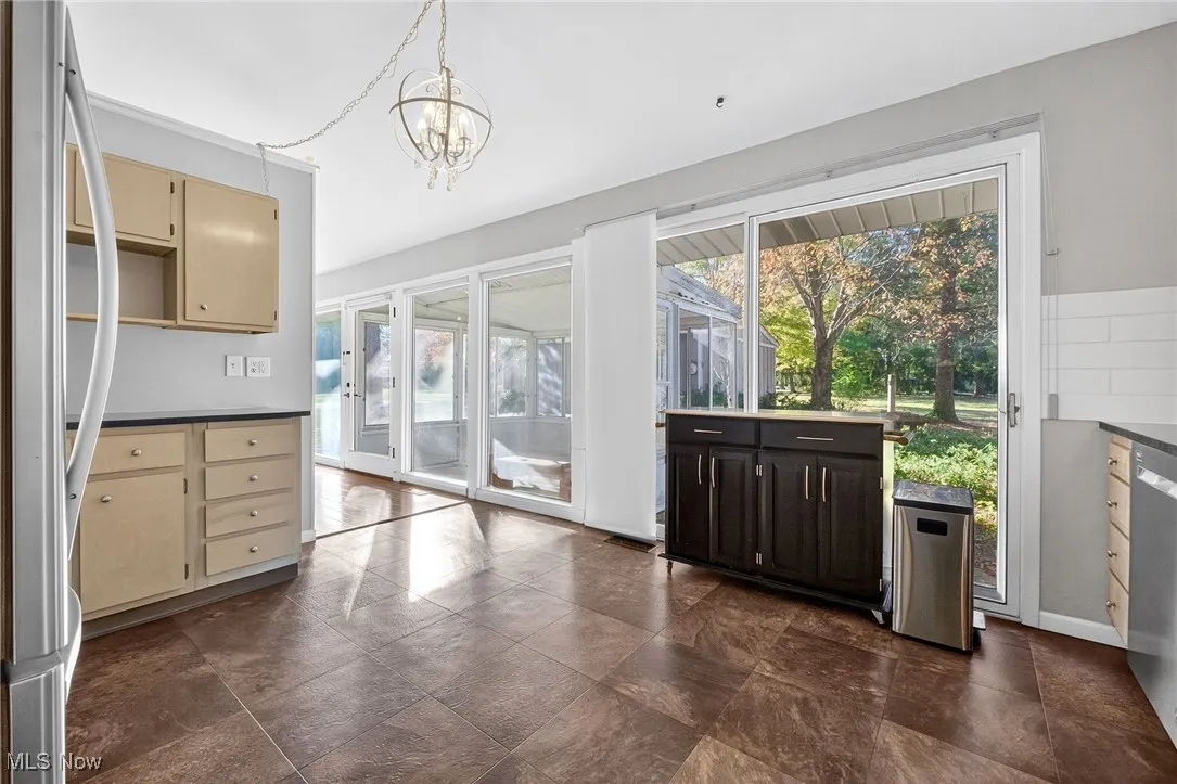 Kitchen featuring stainless steel appliances, dark countertops, pendant lighting, and a chandelier