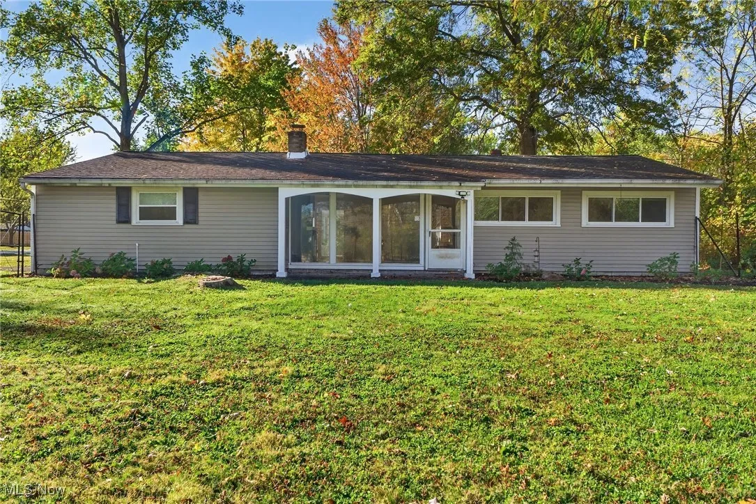 Back of property featuring a chimney and a lawn