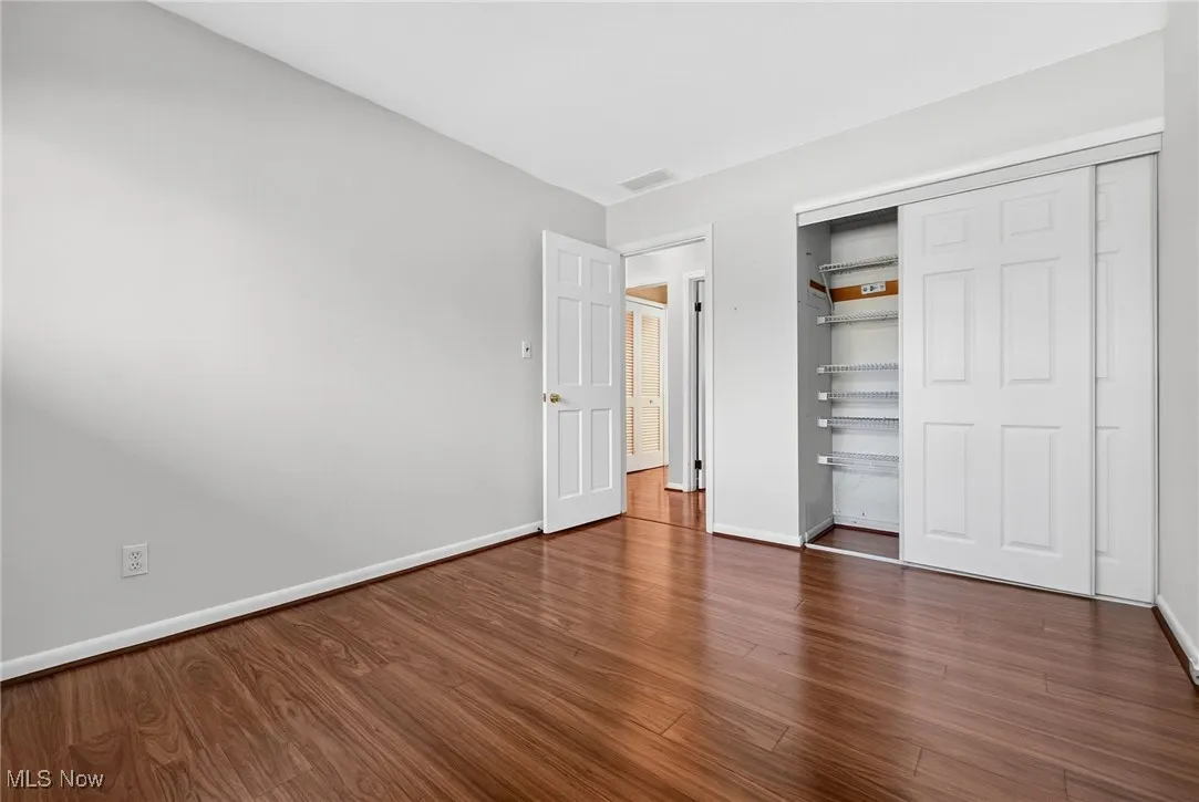 Unfurnished bedroom with dark wood-style floors and a closet