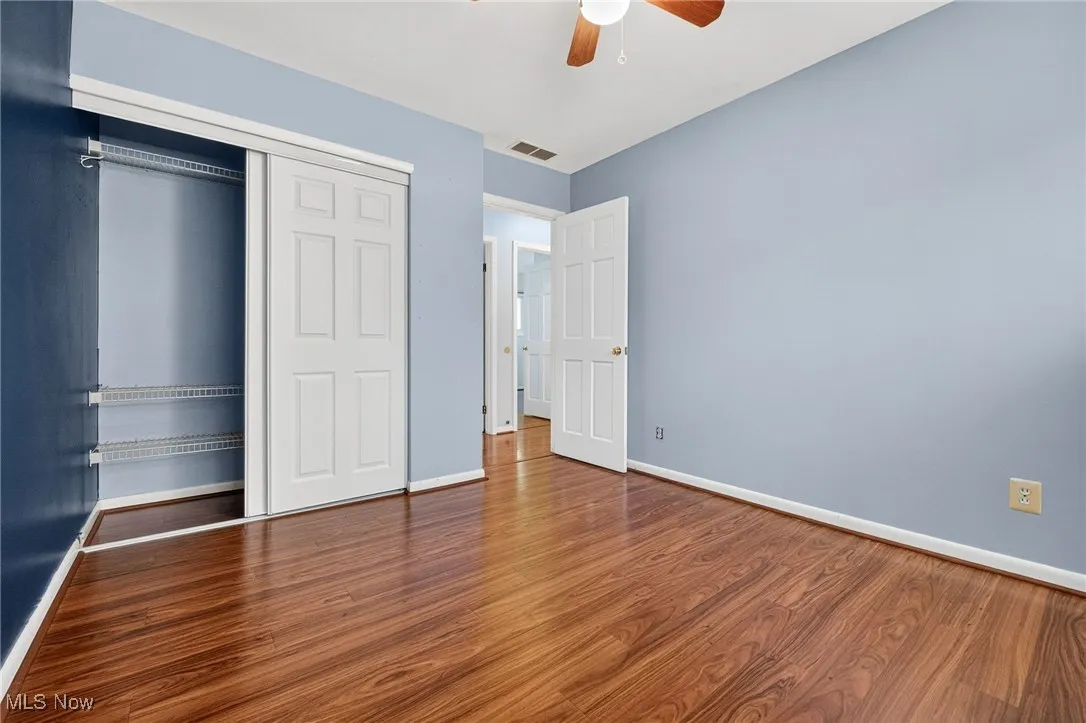 Unfurnished bedroom with a closet, dark wood-style flooring, and a ceiling fan