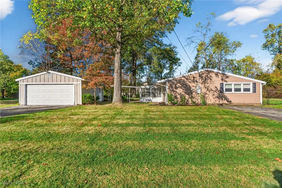 View of green lawn with a sunroom and a garage