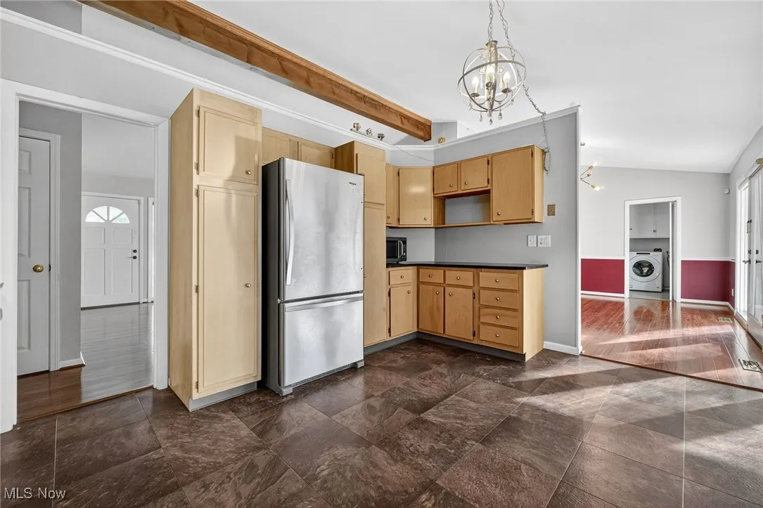Kitchen with stainless steel appliances, dark countertops, pendant lighting, washer / dryer, and a chandelier