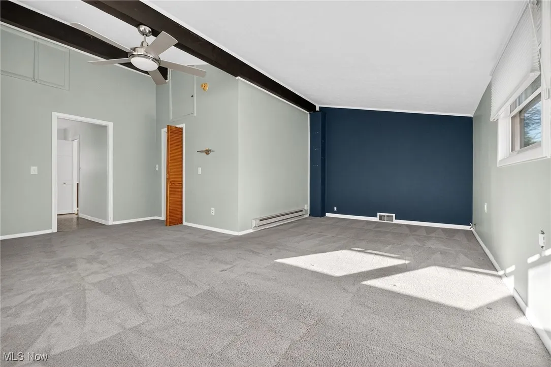 Unfurnished room featuring light colored carpet, a baseboard heating unit, and ceiling fan