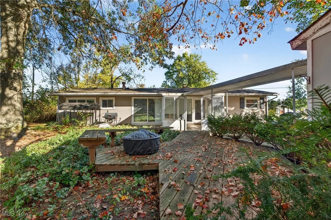 Rear view of house with a fire pit, a sunroom, and a wooden deck