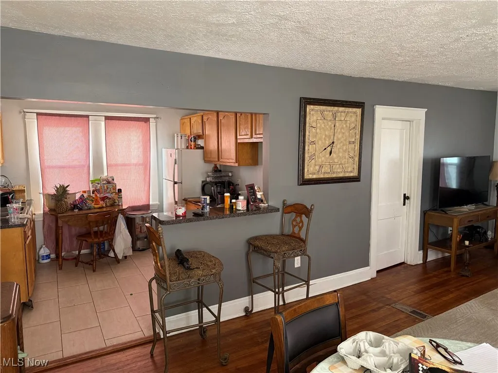 Kitchen featuring a textured ceiling, brown cabinets, light wood-style floors, a kitchen bar, and freestanding refrigerator