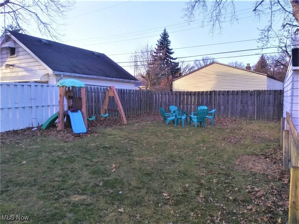Fenced backyard featuring a playground