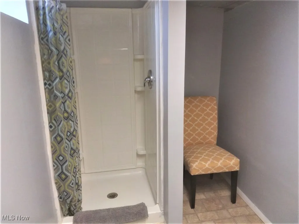Bathroom with a shower stall and baseboards