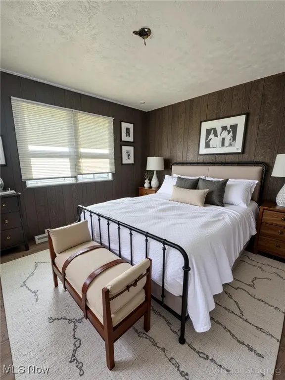 Bedroom featuring a textured ceiling, wood walls, and wood finished floors