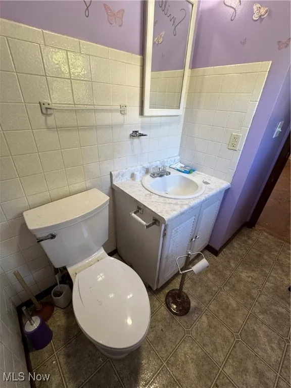 Bathroom with vanity, tile walls, and dark tile patterned floors