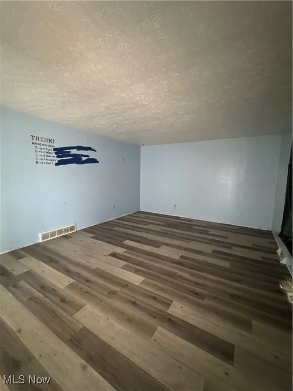 Additional living space with wood finished floors and a textured ceiling