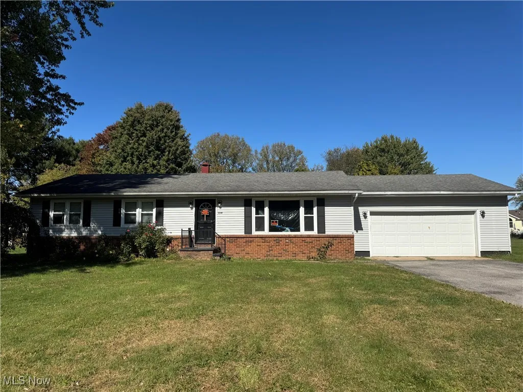 Ranch-style house with a front lawn, asphalt driveway, a chimney, a garage, and brick siding