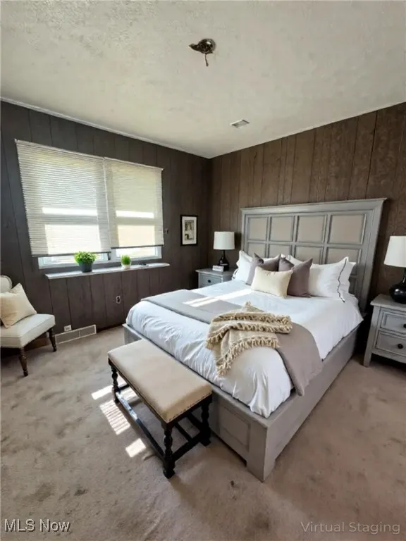 Bedroom with carpet floors, a textured ceiling, and wood walls