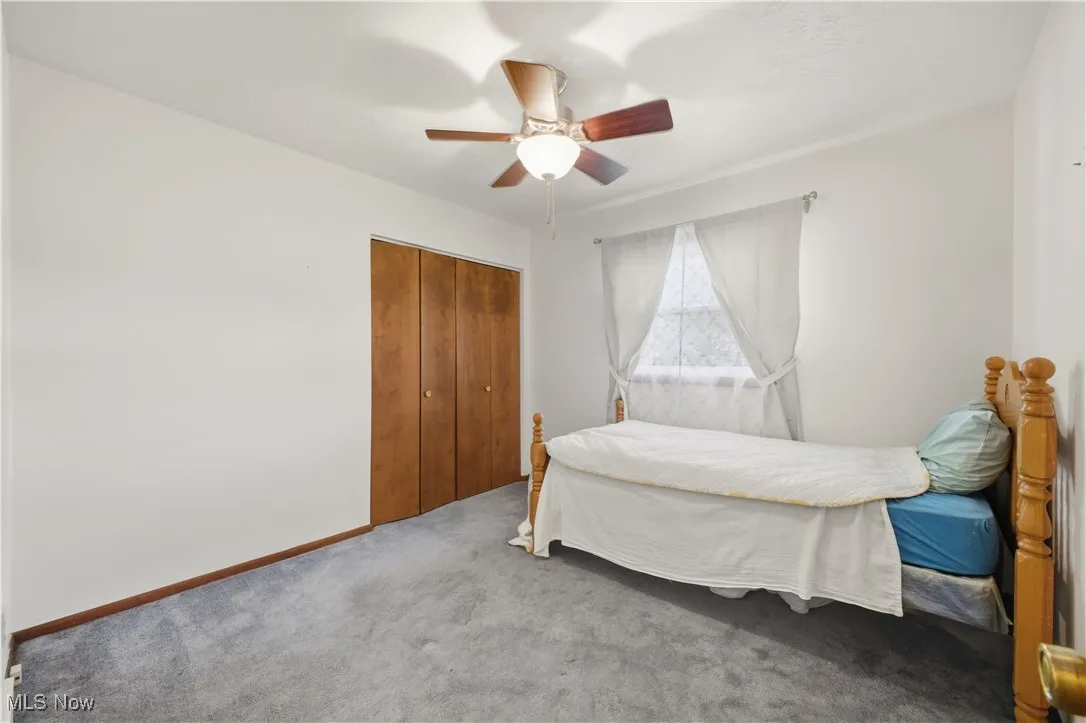 Carpeted bedroom featuring a ceiling fan and a closet