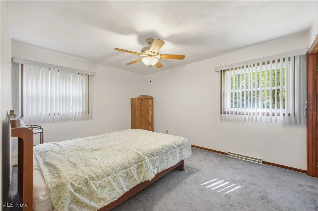 Bedroom with multiple windows, carpet, and a ceiling fan