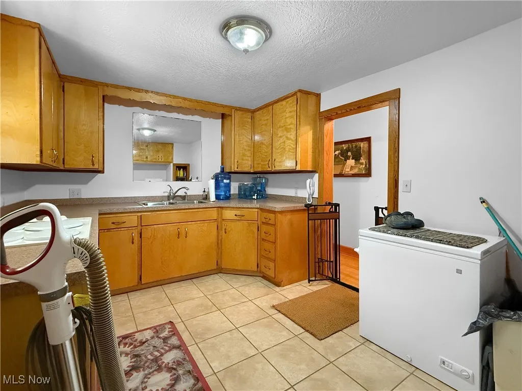 Kitchen featuring light tile patterned floors, a textured ceiling, light countertops, and brown cabinets