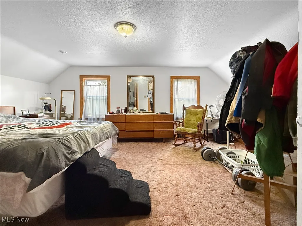 Carpeted bedroom featuring lofted ceiling and a textured ceiling