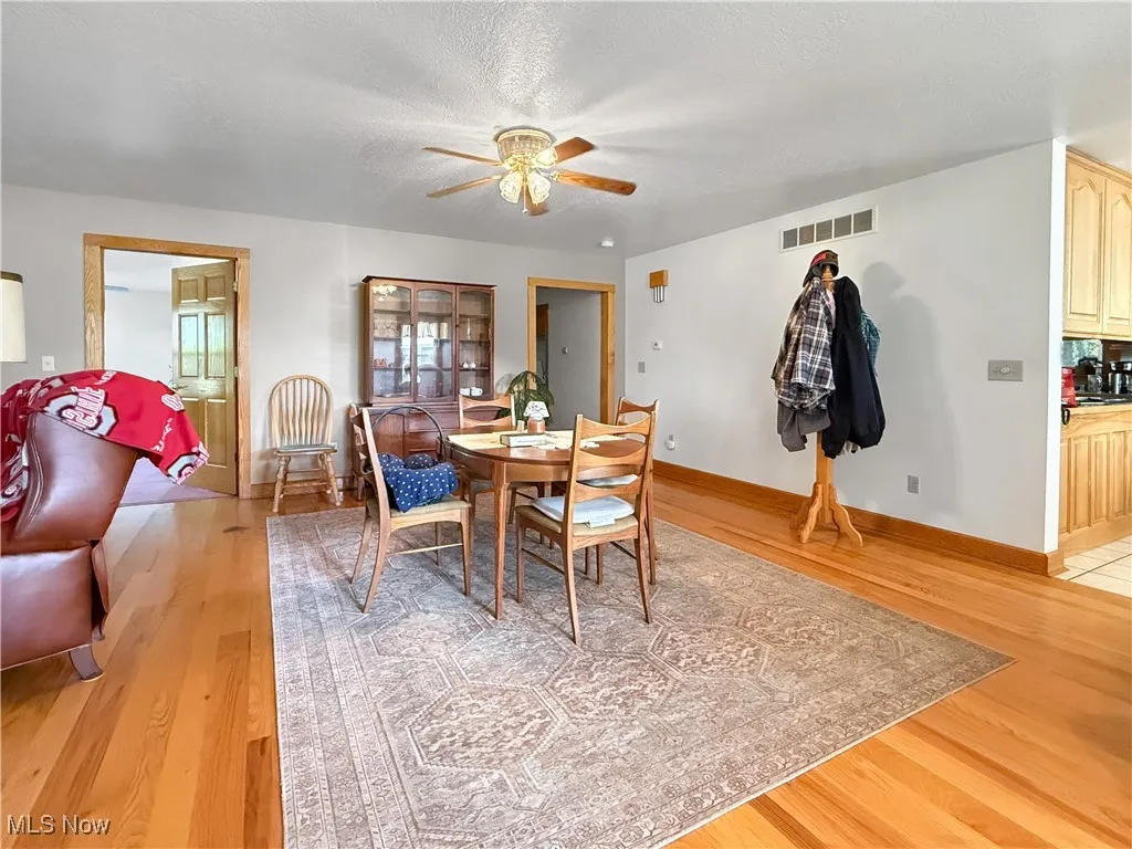 Dining space with light wood-type flooring, a ceiling fan, and a textured ceiling
