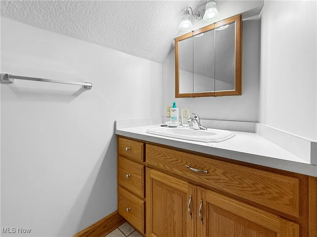 Bathroom with a textured ceiling, vanity, and light tile patterned floors