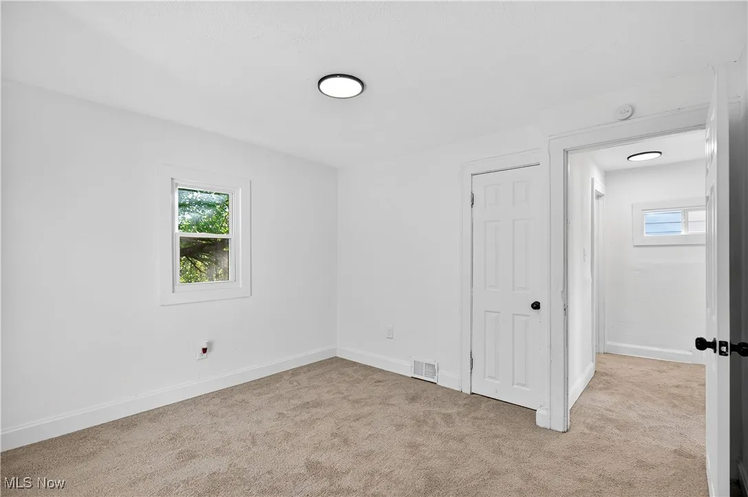 Unfurnished bedroom featuring light carpet and baseboards
