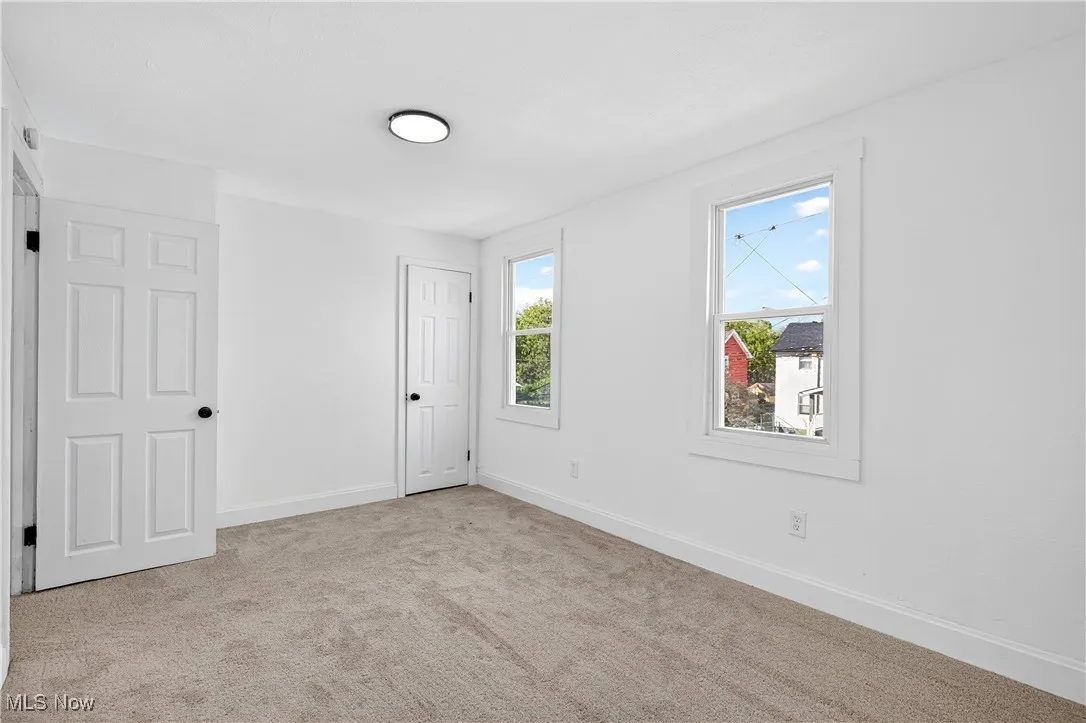 Unfurnished bedroom featuring light carpet and baseboards