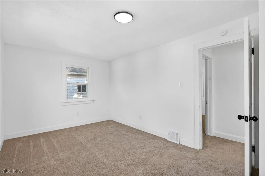 Empty room with light colored carpet and baseboards