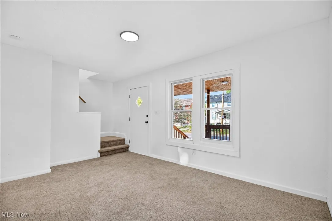 Carpeted foyer entrance featuring stairs and baseboards