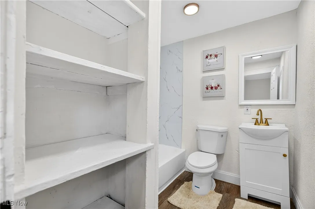 Bathroom featuring dark wood-type flooring, vanity, and bathing tub / shower combination