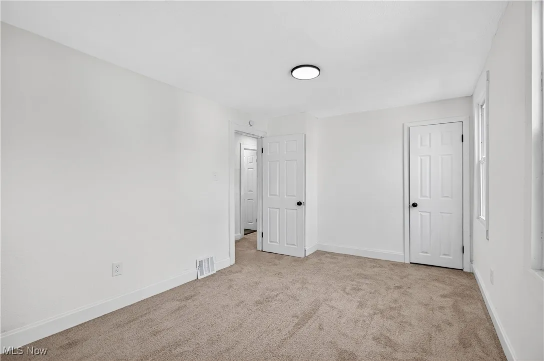 Unfurnished bedroom with light colored carpet and baseboards