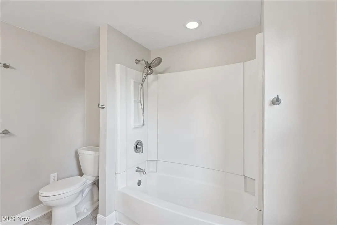 Bathroom with washtub / shower combination and tile patterned flooring