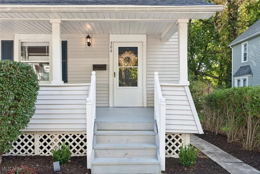 View of exterior entry with a shingled roof and a porch