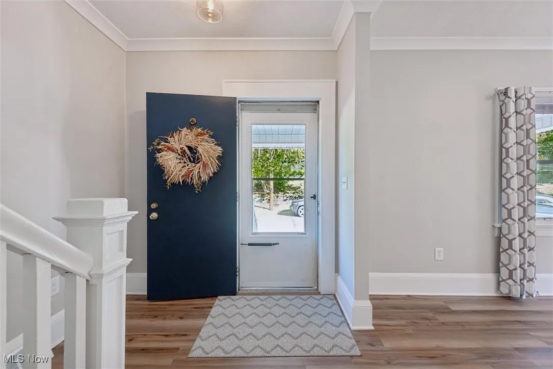 Foyer entrance featuring ornamental molding and light wood finished floors