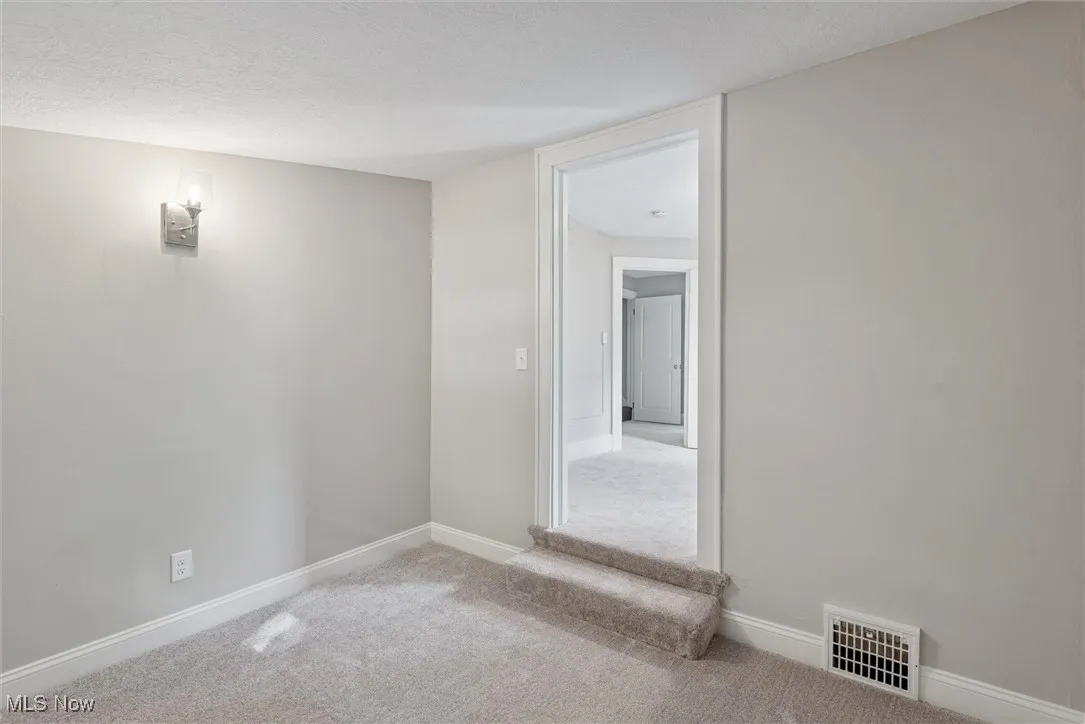 Carpeted spare room featuring a textured ceiling and baseboards