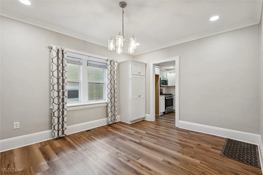Unfurnished dining area featuring light wood finished floors, recessed lighting, a chandelier, and ornamental molding