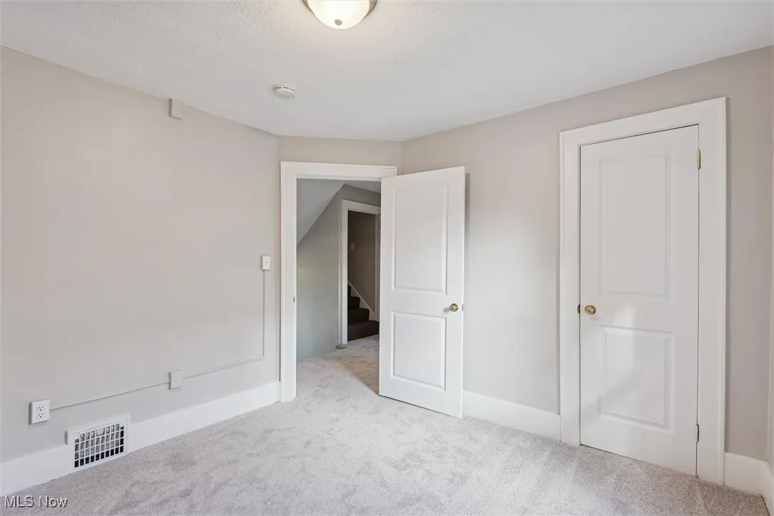 Unfurnished bedroom featuring light carpet and baseboards