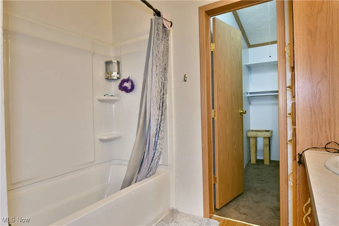 Full bathroom with shower / bath combination with curtain, carpet floors, vanity, and a textured ceiling