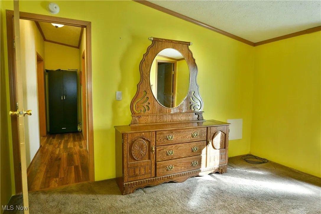 Carpeted bedroom featuring ornamental molding, a textured ceiling, and wood finished floors