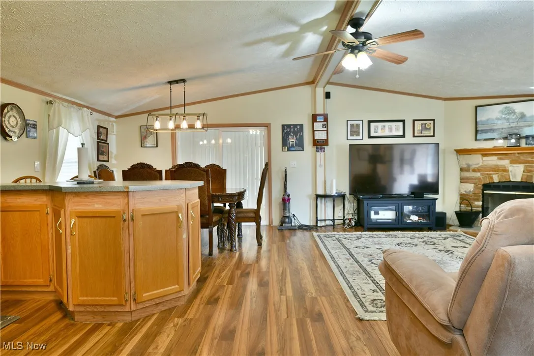 Kitchen with open floor plan, light wood-type flooring, a textured ceiling, ornamental molding, and hanging light fixtures