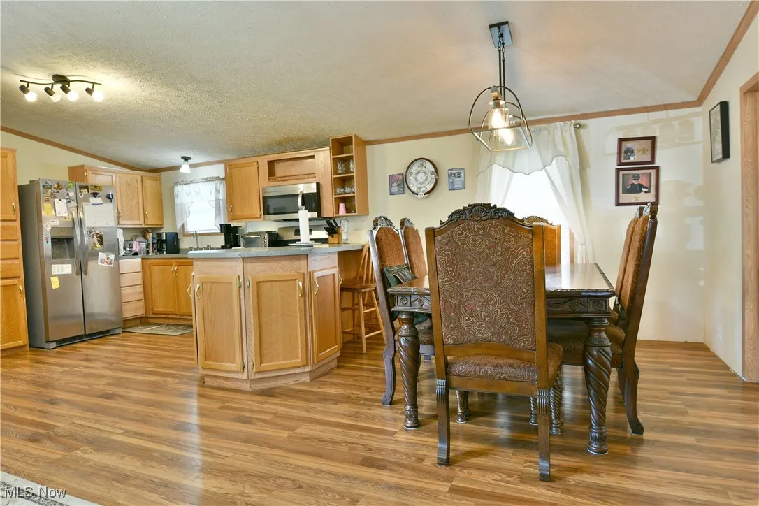 Dining space featuring ornamental molding, light wood-style floors, and a textured ceiling