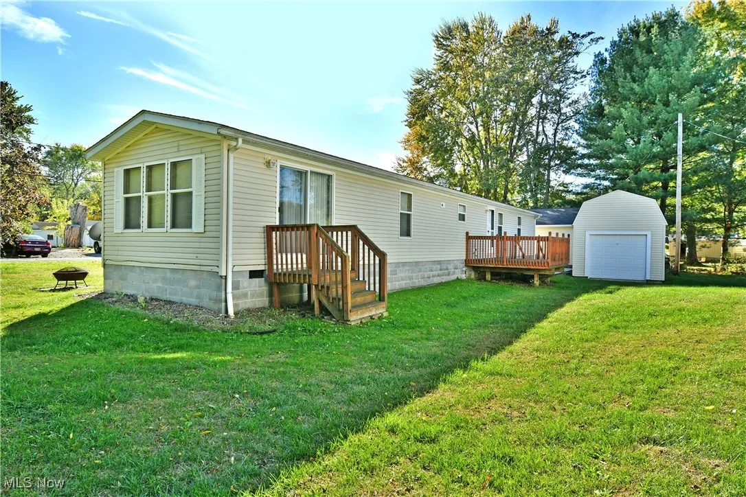 Back of property with a yard, an outdoor structure, a wooden deck, and crawl space