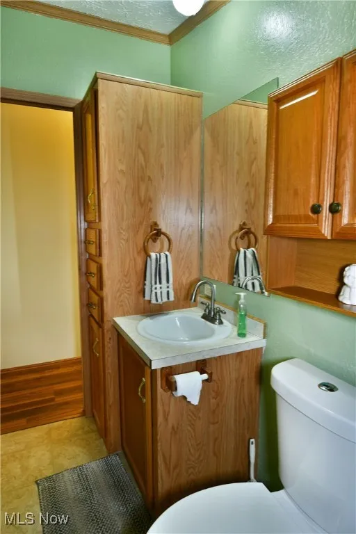 Bathroom featuring ornamental molding, a textured ceiling, and vanity