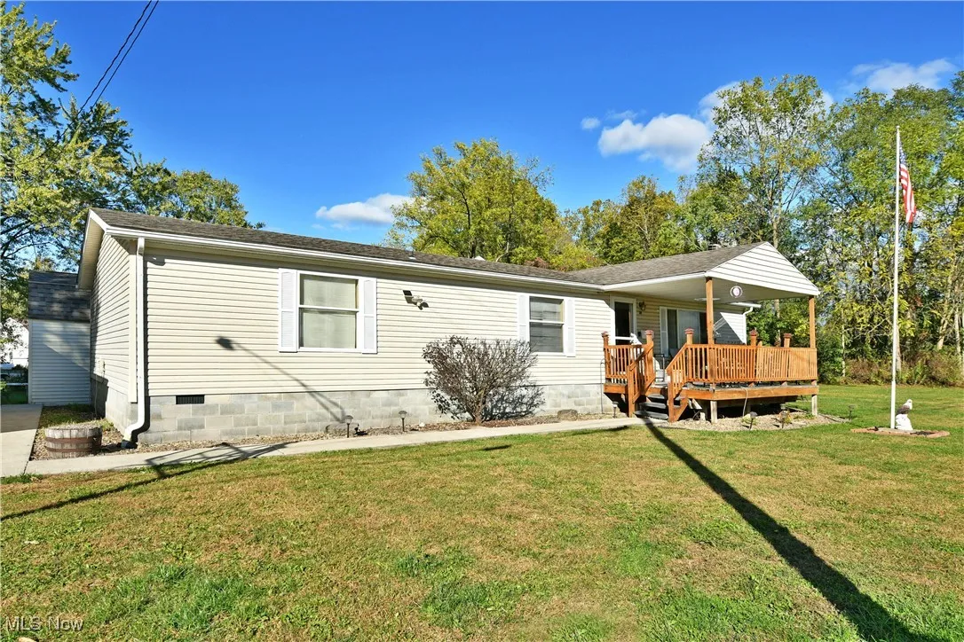 View of front facade featuring a front yard, crawl space, a wooden deck, and a shingled roof