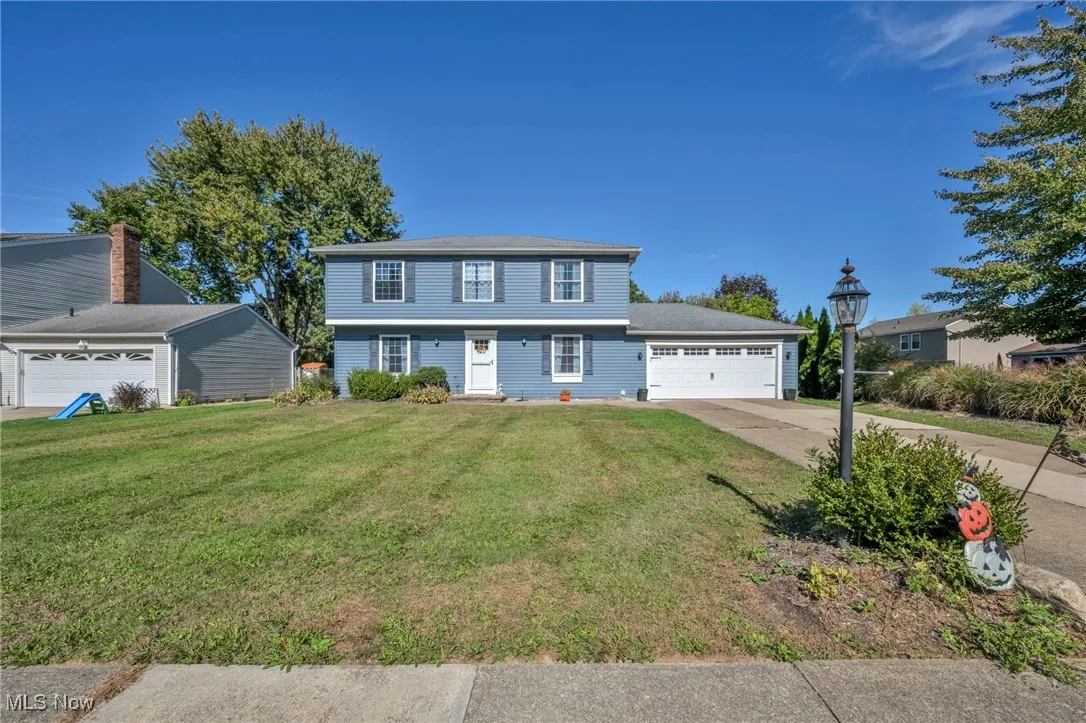 Colonial house featuring a front lawn, driveway, and a garage