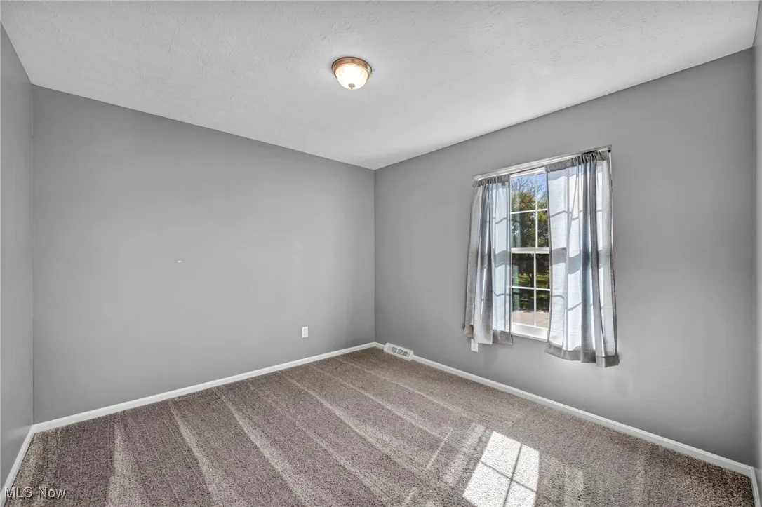 Carpeted empty room featuring baseboards and a textured ceiling