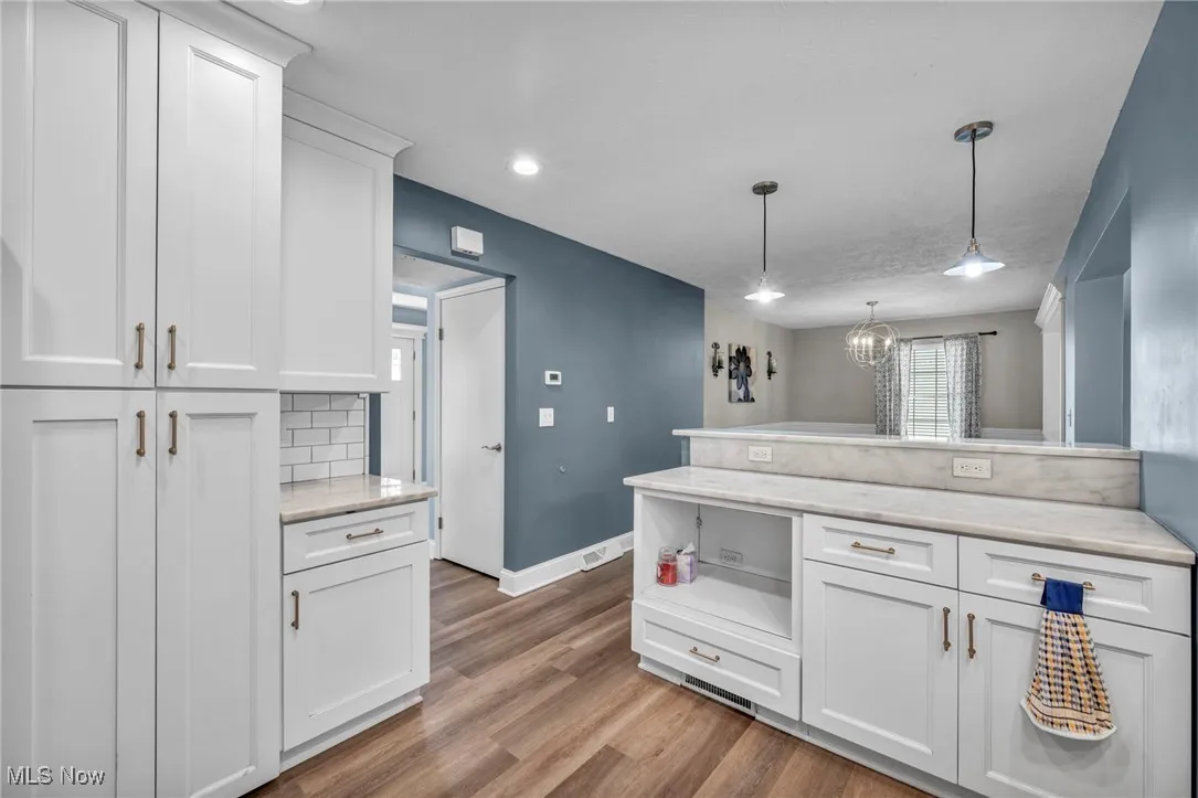 Kitchen with white cabinets, decorative light fixtures, dark wood-style flooring, a peninsula, and open shelves