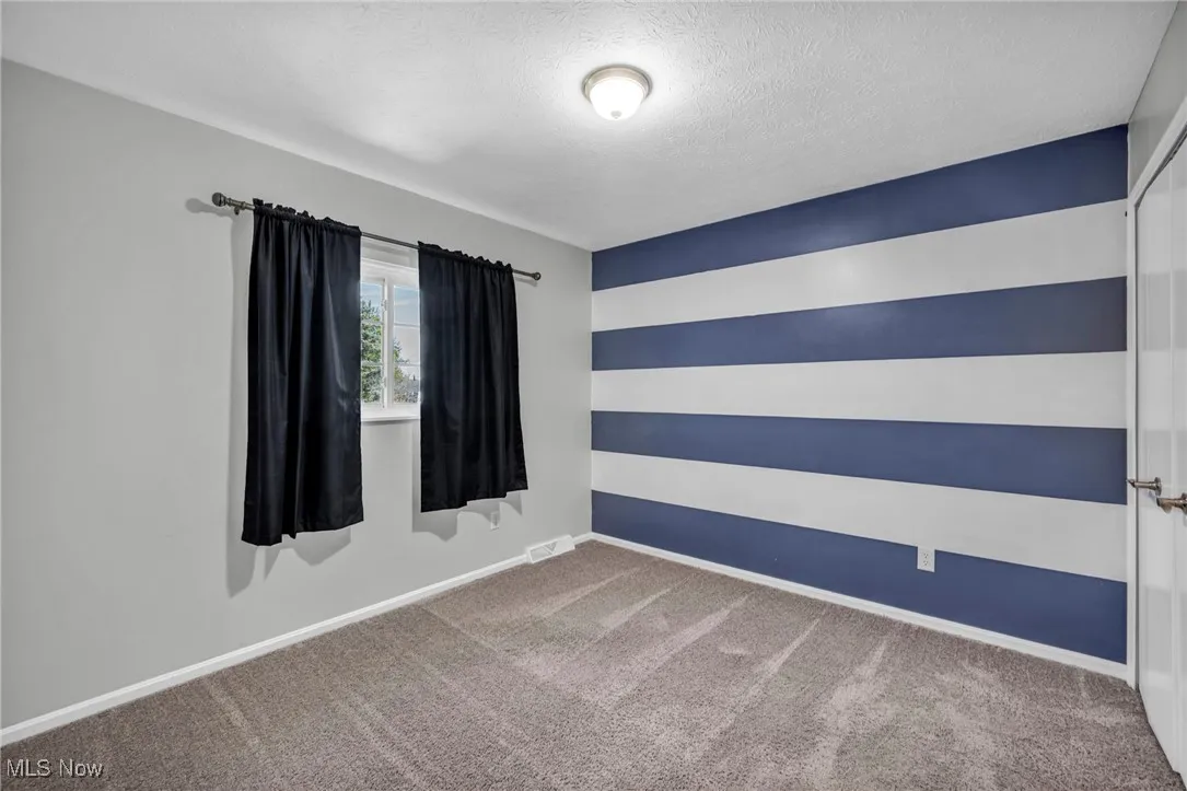 Carpeted empty room with baseboards and a textured ceiling