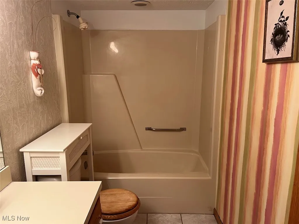 Full bathroom with sink, vanity, shower / tub combo, commode and tile flooring