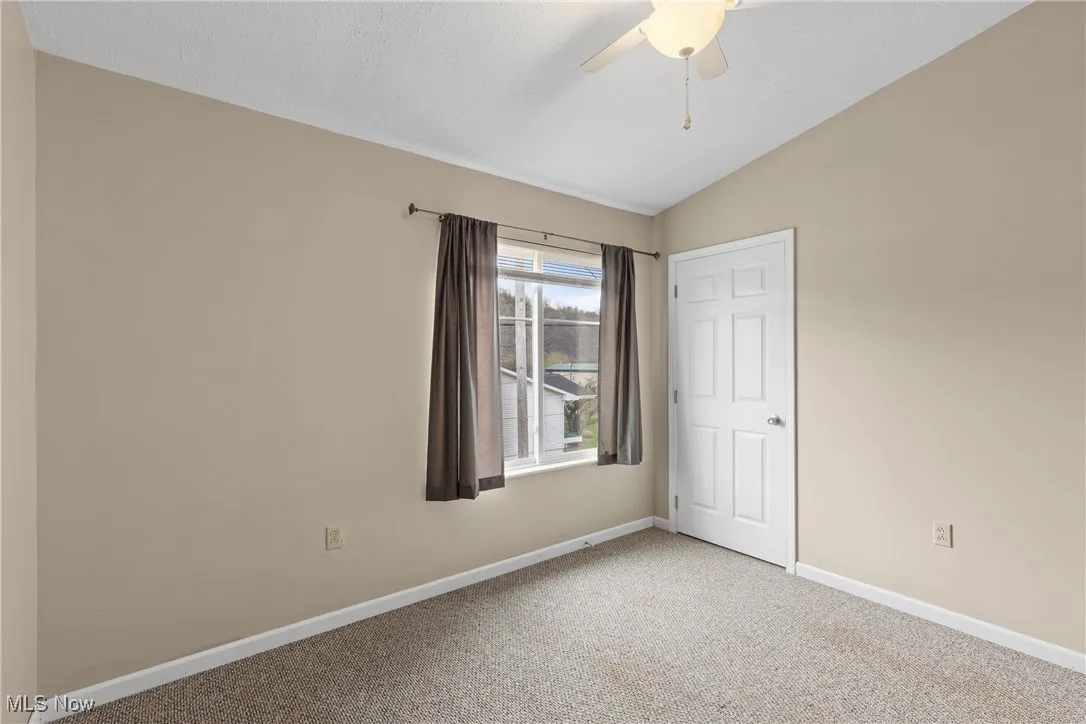 Unfurnished bedroom featuring carpet flooring, lofted ceiling, and ceiling fan