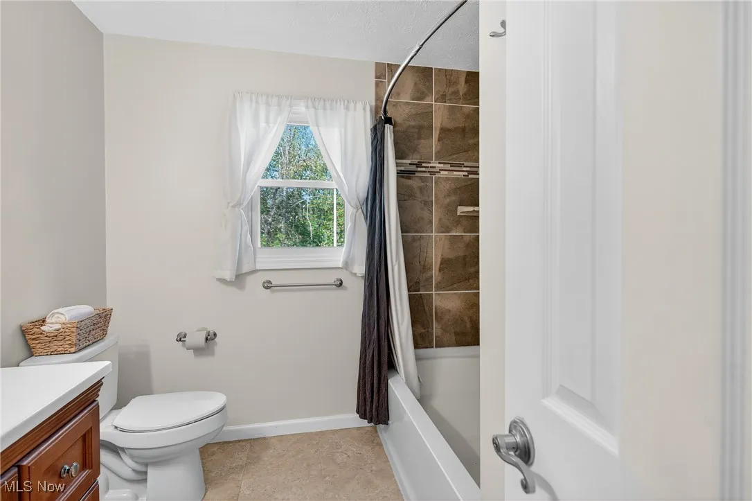 Full bath with shower / tub combo, vanity, and light tile patterned floors