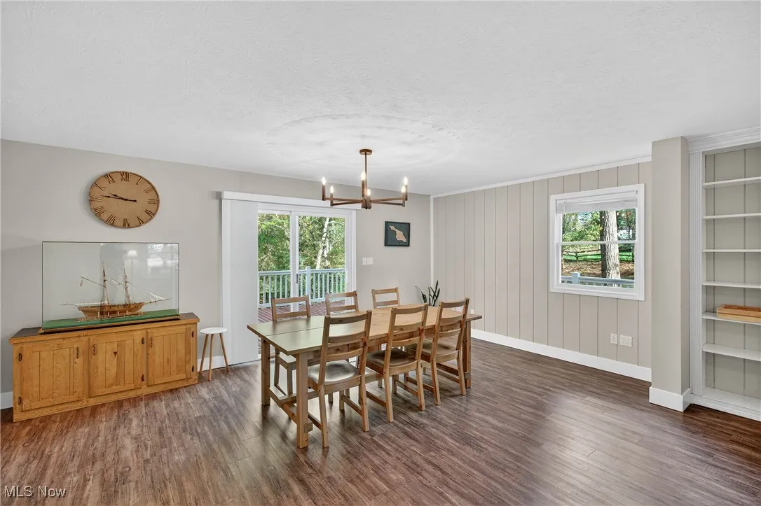 Dining space featuring dark wood-type flooring, a textured ceiling, a chandelier, and built in features