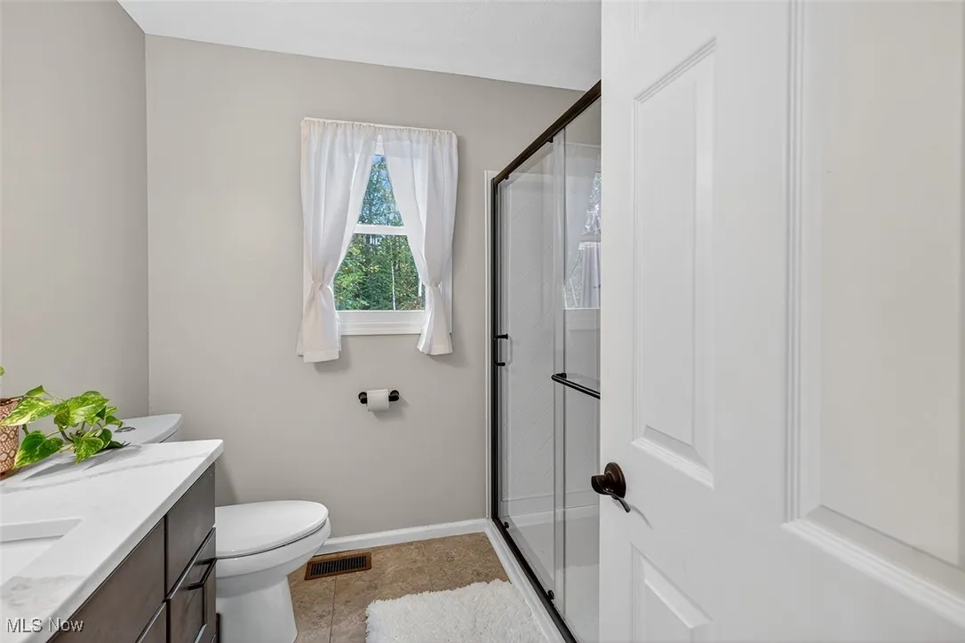 Full bath featuring vanity, a stall shower, and light tile patterned flooring